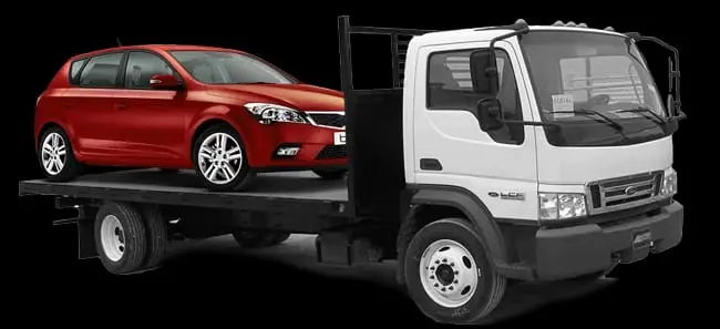 A red car is parked on the back of a white truck.